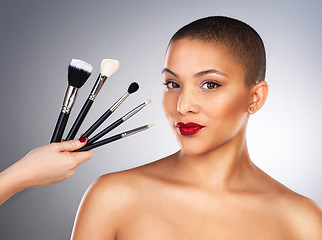 Image showing Not every artist uses paper and paint. Studio shot of a hand holding makeup brushes next to a beautiful young womans face.