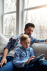 Image showing Hes learning even when relaxing. a little boy using a digital tablet with his father at home.