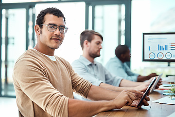 Image showing Hes in the creative line of work. Portrait of a young businessman using a digital tablet with his colleagues in the background.