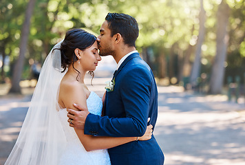 Image showing Loving husband kissing his beautiful bride on the forehead. Happy in love newlywed couple standing together sharing romantic moment outdoors