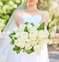 Image showing Close up of bride holding a bouquet of flowers while standing outside on a sunny day. Beautiful wedding bouquet of white roses
