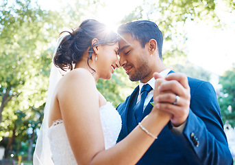 Image showing Bride and groom holding hands and touching foreheads while dancing outside. Mixed race newlyweds enjoying romantic moments on their wedding day. Happy young romantic couple sharing their first weddin