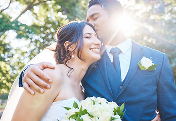 Image showing Beautiful young couple on their wedding day. Groom kissing his joyful bride on the head while standing with his arm around her