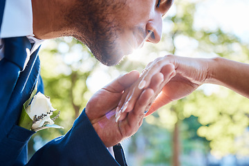 Image showing Close up of young handsome charming groom kissing his brides hand while standing outside on a summer day in nature. Gentlemen kissing womans hand after wedding proposal