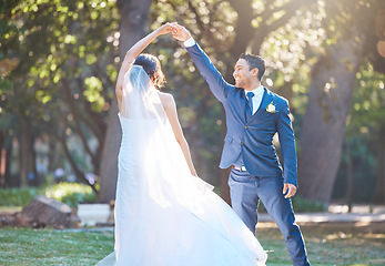 Image showing Joyful bride and groom sharing a dance in nature. Groom spins his bride during romantic dance at park on their wedding day