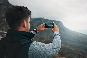 Image showing What we see mainly depends on what we look for. a young man taking photos while out on a hike.