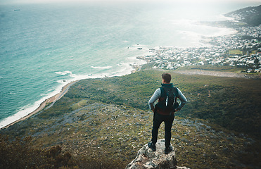 Image showing Roam far and wander wide. a young man looking at the view from a cliff while out on a hike.