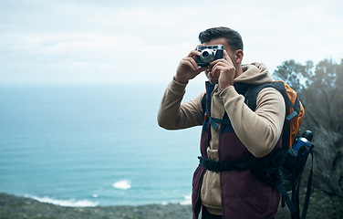 Image showing Be a true traveller, not a temporary tourist. a young man taking photos while out on a hike.