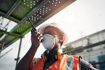 Image showing Its a beautiful day to build your dream. a young woman using a walkie talkie while working at a construction site.