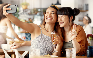 Image showing Capturing special moments together. two friends taking selfies using a smartphone at a restaurant.