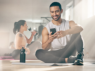 Image showing Im inviting my friends to join me next time. a man using his cellphone while on a break at the gym.