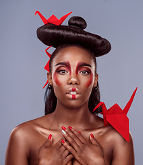 Image showing Less division, more integration. Studio shot of a beautiful young woman wearing Asian inspired makeup and posing with origami against a grey background.