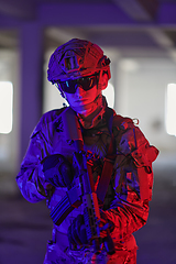 Image showing A professional soldier undertakes a perilous mission in an abandoned building illuminated by neon blue and purple lights