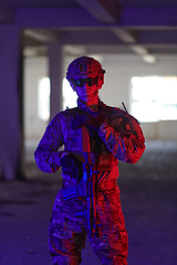 Image showing A professional soldier undertakes a perilous mission in an abandoned building illuminated by neon blue and purple lights