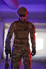 Image showing A professional soldier undertakes a perilous mission in an abandoned building illuminated by neon blue and purple lights