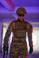 Image showing A professional soldier undertakes a perilous mission in an abandoned building illuminated by neon blue and purple lights