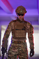 Image showing A professional soldier undertakes a perilous mission in an abandoned building illuminated by neon blue and purple lights