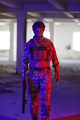 Image showing A professional soldier undertakes a perilous mission in an abandoned building illuminated by neon blue and purple lights