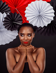 Image showing Why choose a single style when you can sample both. Studio shot of a beautiful young woman posing with a origami fans against a black background.