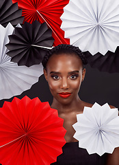 Image showing Fashion has the power to connect cultures. Studio shot of a beautiful young woman posing with a origami fans against a black background.