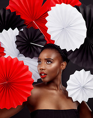 Image showing So many fans and only two hands. Studio shot of a beautiful young woman posing with a origami fans against a black background.