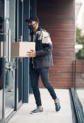 Image showing Hello, your delivery is here. a masked young man delivering a package to a place of residence.