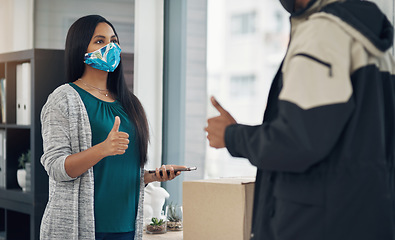 Image showing Thats why youre the best. a masked young woman showing thumbs up while receiving a delivery at home.