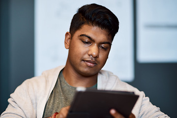 Image showing The tool to get the design done quicker. a young businessman using a digital tablet in a modern office.