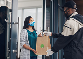 Image showing The best and safest in the food delivery business. a masked young woman receiving a takeout delivery at home.