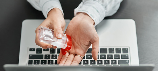 Image showing Stay protected, stay productive. a businesswoman using hand sanitiser while using a laptop in a modern office.