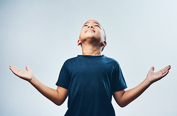 Image showing Thank you God for everything. Studio shot of a cute little boy opening his arms and looking up against a grey background.