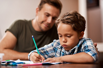 Image showing Dad is here to help whenever I struggle. a man sitting with his son while he does his homework.