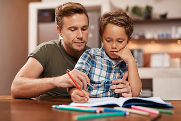 Image showing Youre doing well, buddy. a man sitting with his son while he does his homework.