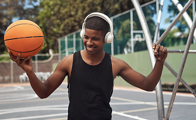 Image showing Watch me slam dunk. a sporty young man listening to music while playing basketball on a sports court.