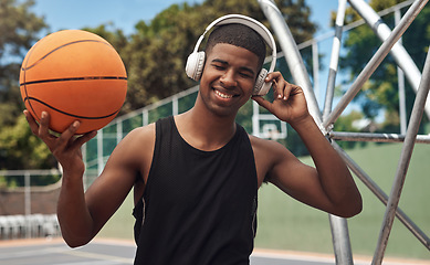 Image showing Playing basketball automatically makes you cool. a sporty young man listening to music while playing basketball on a sports court.