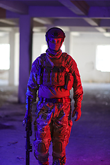 Image showing A professional soldier undertakes a perilous mission in an abandoned building illuminated by neon blue and purple lights