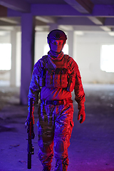 Image showing A professional soldier undertakes a perilous mission in an abandoned building illuminated by neon blue and purple lights