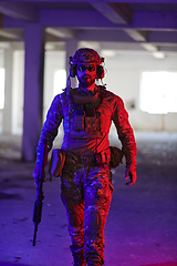 Image showing A professional soldier undertakes a perilous mission in an abandoned building illuminated by neon blue and purple lights