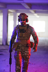 Image showing A professional soldier undertakes a perilous mission in an abandoned building illuminated by neon blue and purple lights