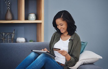 Image showing When your saving finally paid off. an attractive young woman using a digital tablet and credit card on the sofa at home.