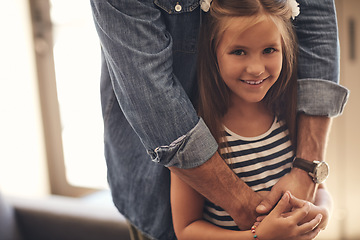 Image showing Dads always there to show that her cares. Portrait of an adorable little girl standing with her father’s arms around her at home.