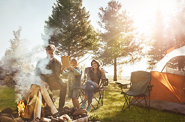 Image showing Life is better around the campfire. a young family camping in the forest.
