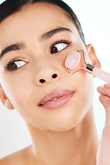 Image showing Rolling away those wrinkles. Studio shot of an attractive young woman using a face massager against a light background.