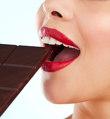 Image showing Something sweet. Studio shot of an unrecognizable young woman biting into a slab of chocolate against a light background.