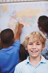 Image showing Im going to travel the world one day. A young boy standing in the classroom as his friends and teacher look over a world map.