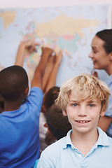 Image showing Excited about geography. A young boy standing in the classroom as his friends and teacher look over a world map.
