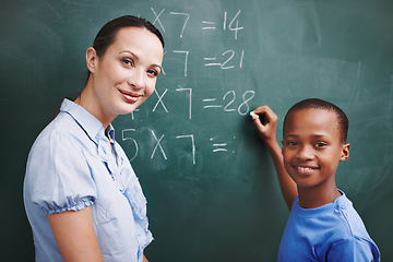 Image showing Patient and caring teacher. A young boy and his teacher looking at each other while he does sums on the board.