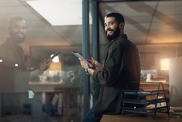 Image showing The gadget that matches his grind. a young businessman using a digital tablet during a late night in a modern office.