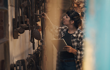 Image showing Metal works management made easier with modern tech. a young woman using a digital tablet while working at a foundry.