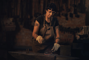 Image showing Hard work is always the way. a young woman hitting a hot metal rod with a hammer in a foundry.